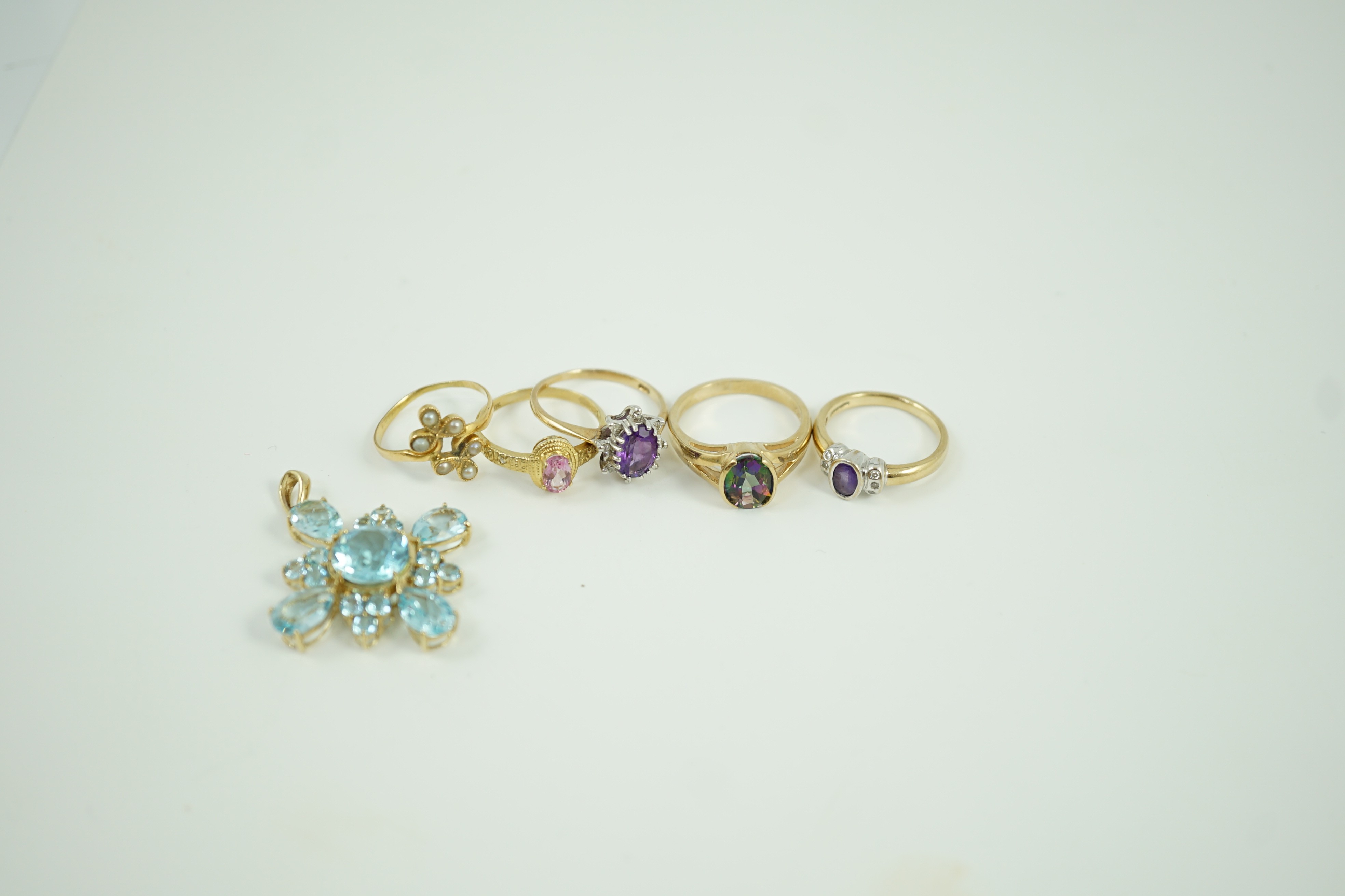 Four assorted modern 9ct gold and gem set rings, a white metal and seed pearl ring and a 9ct gold and blue stone cluster set pendant, 33mm, gross weight 17.9 grams.